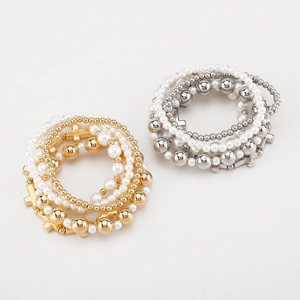 Detail of multi-layer beaded bracelets with silver and gold finish and cross pendants