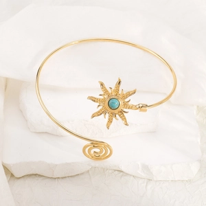 Gedetailleerde weergave van gouden zonne-armband met turquoise steen op een voetstuk