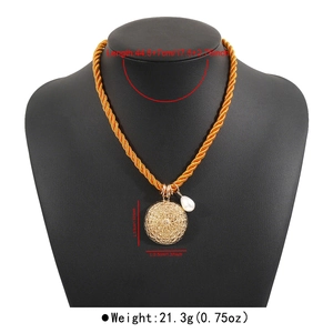 Dettaglio della collana bohémien con ciondolo rotondo traforato e perla a goccia dorata