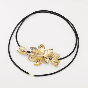 Close-up of golden tulip floral ornament with brushed metal texture on a black cord belt