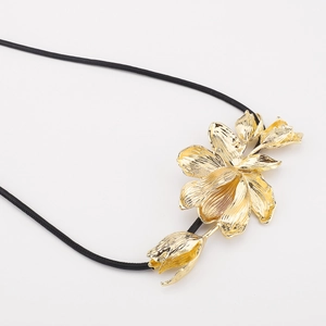 Detail view of a vintage gold tulip pendant with a black leather cord belt chain