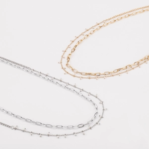 Détail de ceintures à double chaîne dorée et argentée avec de petites perles blanches