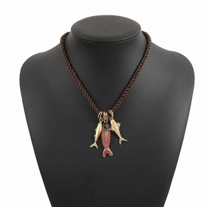 Dettaglio del ciondolo a forma di pesce smaltato su una collana in corda intrecciata