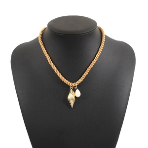 Collana a corda dorata con ciondolo a conchiglia e perla a goccia su manichino nero