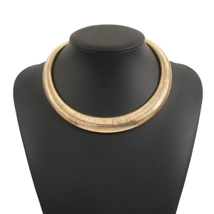 Close-up of golden heavy snake bone choker necklace with thick metallic spiral texture