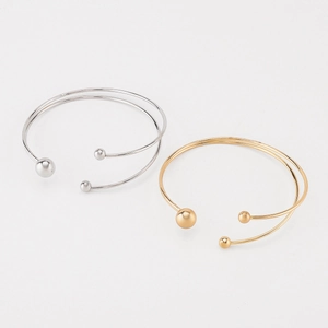 Gros plan sur le bracelet ouvert double couche minimaliste avec billes en or et argent