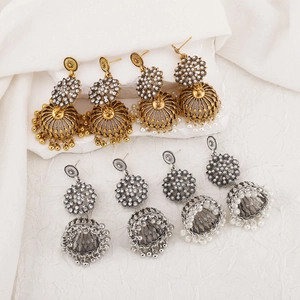 Detailed view of bohemian jhumka earrings in gold and silver finish with rhinestones