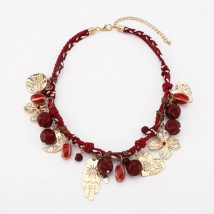 Dettaglio della collana boho in corda rossa con mano di Fatima e pendenti dorati