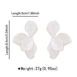 Detail view of large white floral earrings with gold edges and marble texture