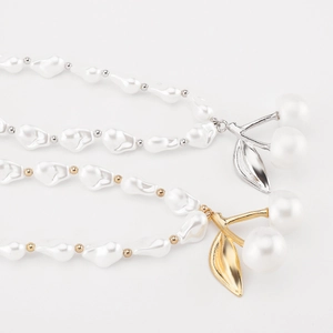 Détails du collier de perles baroques avec pendentifs cerise dorés et argentés