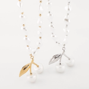 Détail d'un collier de perles baroques avec pendentif cerise en finitions or et argent
