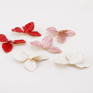 Detailed macro view of triple-petal flower earrings in vibrant red, pink, and white marble