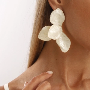 Elegant oversized ivory marble textured flower earrings worn by a model in natural light