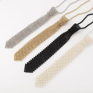 Détail de colliers cravates en perles aux finitions argent, or, noir et blanc nacré