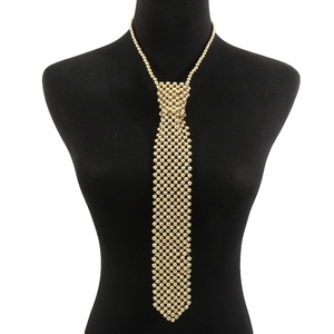 Détail d'un collier cravate en perles dorées avec une texture en métal tissé de luxe