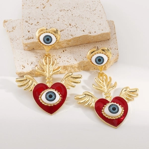 Detailansicht von Evil Eye Ohrringen mit goldenen Flügeln und rotem Herz-Öltropfen
