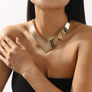 Close-up of a gold V-shaped textured metal choker necklace on a model for a modern look