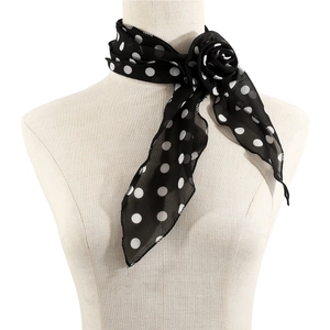 Detail of a chic black silk scarf with white polka dots tied into a stylish rose knot