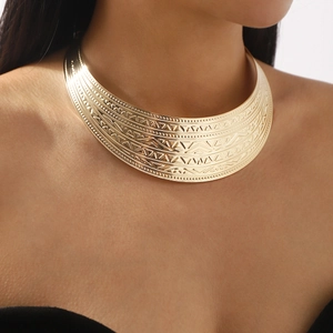 Detailed close-up of wide golden metal choker featuring tribal geometric textured engravings