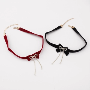 Detail of velvet chokers with crystal bow pendants and tassels in red and black colors