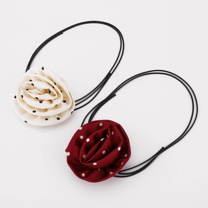 Detailed view of handmade satin polka dot rose flower hair ties in cream and burgundy