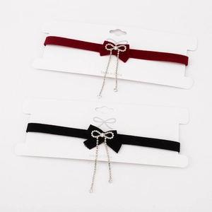 Detail of velvet bow chokers in red and black with hanging rhinestone tassel chains