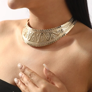 Close-up of golden wide choker with embossed tribal geometric patterns on model