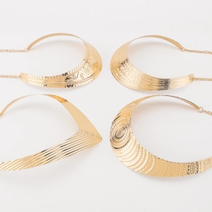 Detail view of four gold metal chokers with ethnic textures and adjustable lobster clasps