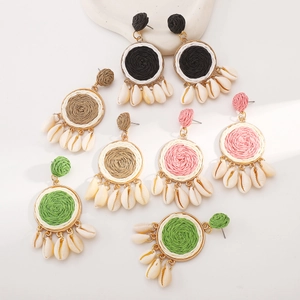 Detail of bohemian raffia woven earrings with seashell pendants in multiple colors