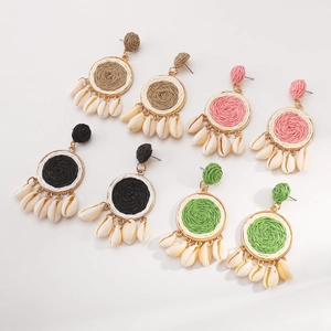 Detail showing four pairs of colorful woven raffia hoop earrings with natural cowrie shells