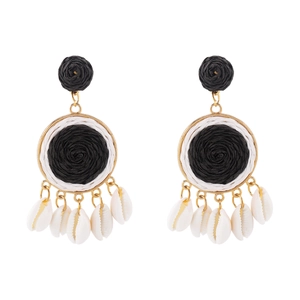 Detail of bohemian raffia hoop earrings with woven texture and small sea shells