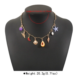 Dettaglio di ciondoli a conchiglia e peperoncino su collana boho chic dorata