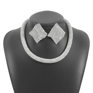 Detailansicht von silbernem Strass-Halsband und großen rautenförmigen Ohrsteckern