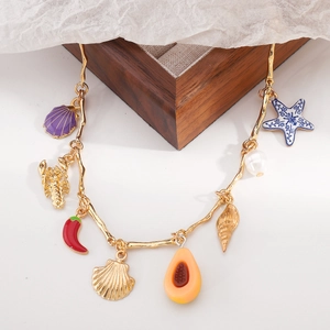 Dettaglio della collana bohémien oceano con conchiglie, perle e ciondoli corallo su catena oro