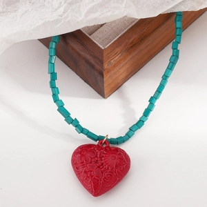 Dettaglio del pendente a cuore rosso con motivi floreali e perline quadrate color teal