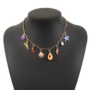 Dettaglio di collana bohémien dorata con ciondoli marini colorati su un modello di collo