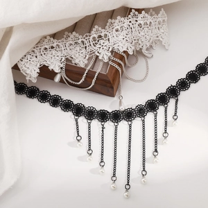 Detail of lace chokers with metal fringe chains and faux pearl pendants in black and white