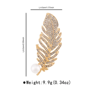 Macro detail of gold feather brooch with crystals and pearl showing 6.5cm height