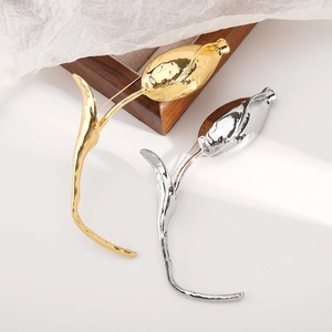 Detail of tulip brooches in gold and silver with textured metal finish and sleek design