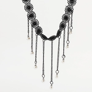 Detail of gothic black lace choker featuring metal chains and white pearl tassels
