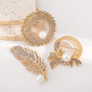 Elegant gold brooches with sparkling crystals and pearls in feather and bow designs