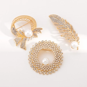 Close-up of gold feather and bow pearl brooches with sparkling rhinestone detail