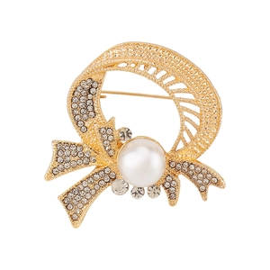 Detailed view of luxury gold bow brooch featuring sparkling crystals and a large pearl