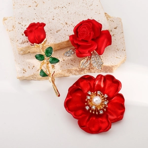 Détails de broches fleurs rouges avec roses en émail et perles sur texture de pierre
