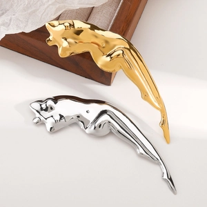 Polished gold and silver leaping panther metal brooches on white background