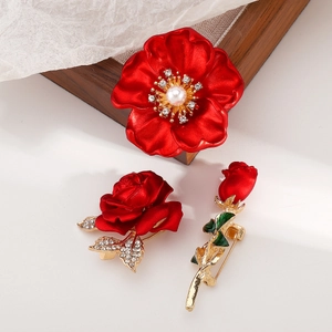 Détail de broches roses rouges avec placage or, strass brillants et perles blanches