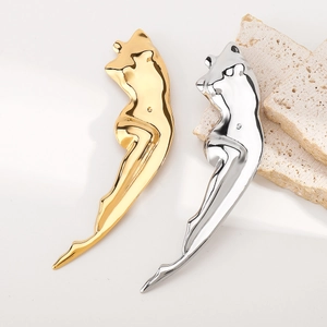 Polished gold and silver feminine body silhouette brooches on travertine stone