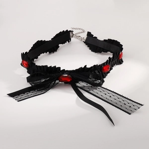 Close-up of black lace choker with dark red oval gemstones and a large mesh bow