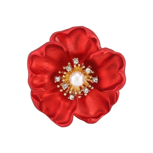 Détail d'une broche rose rouge aux pétales mats avec perle centrale et cristaux brillants