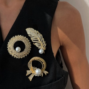 Elegant gold pearl brooches with rhinestones on a black suit jacket for women